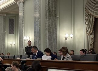 Will A Congressional Boar’s Head Thwart Thumann Nomination? Senate Commerce Committee Chairman Ted Cruz (R-Tex.) is seated next to Minority Leader Maria Cantwell (D-Wash.) and Sen. Amy Klobuchar (D-Minn.)